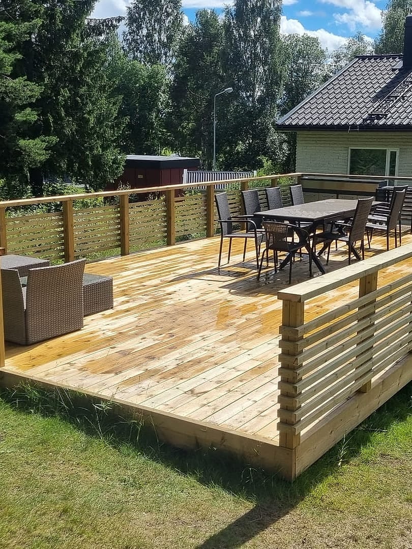 Nybyggd träaltan med spjälräcke, matgrupp och loungemöbler
